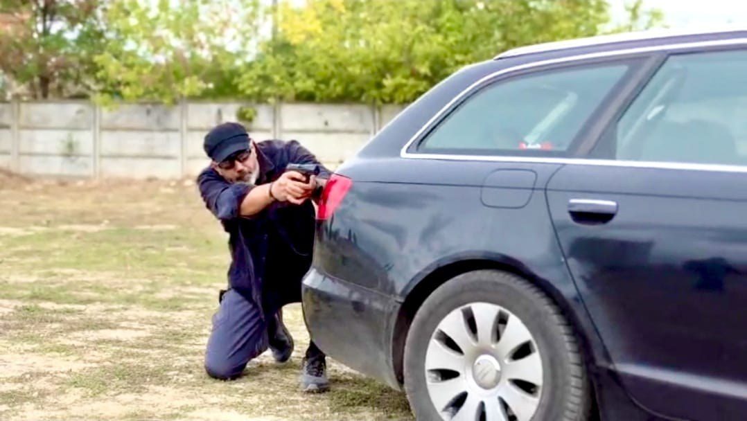 Trainee practising shooting beside a vehicle